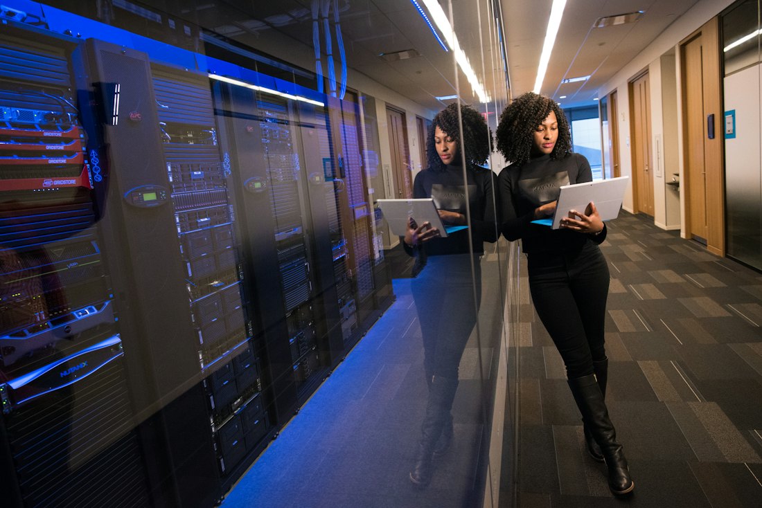 Profissional de TI com um tablet ao lado de servidores em um data center